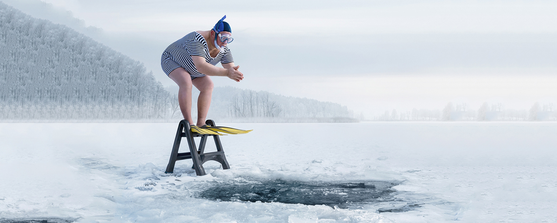 Man prepares to dive into frozen lake hole.