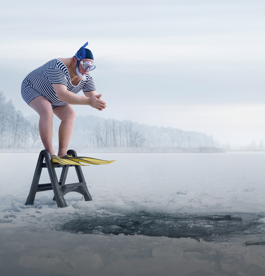 Man prepares to dive into frozen lake hole.