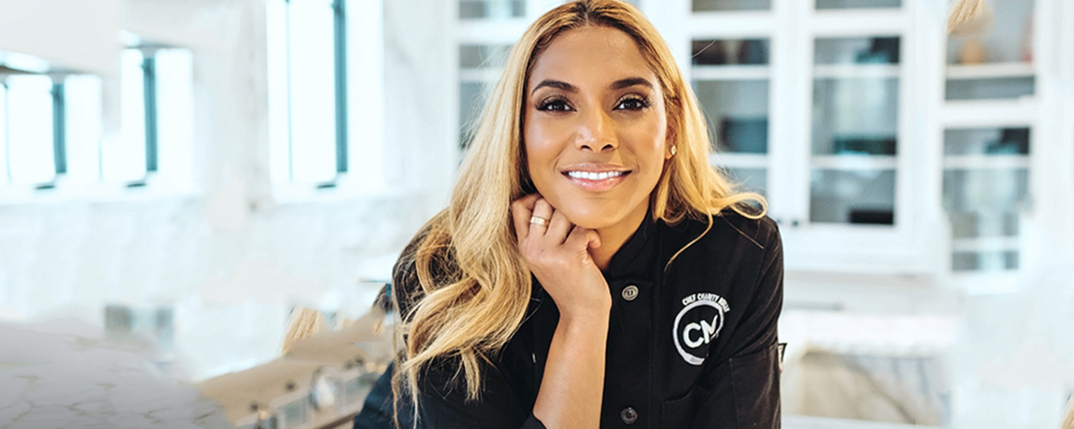 A professional chef poses with her cookbook.