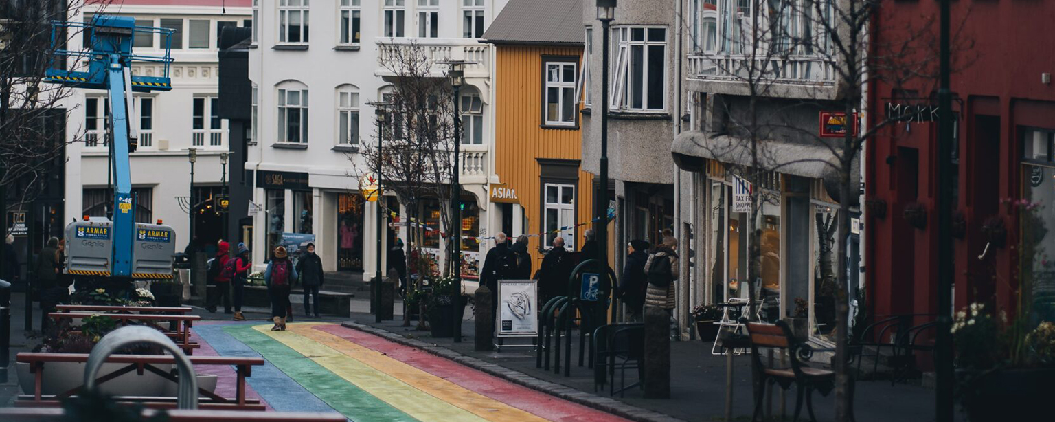 Rainbow street path leading through colorful city buildings.