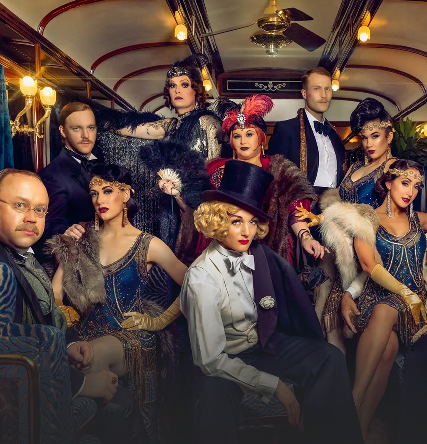 Group of people in 1920s style train car.