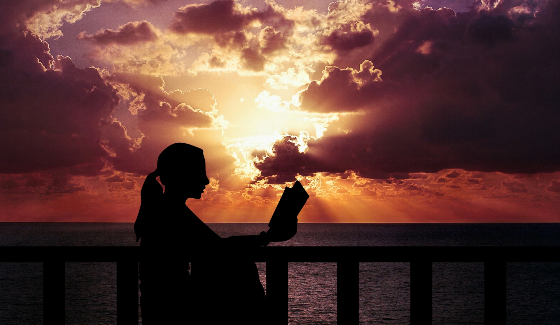 Woman reading book at sunset