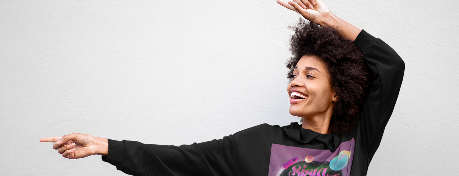 Woman models black hoodie with afro-centric design.