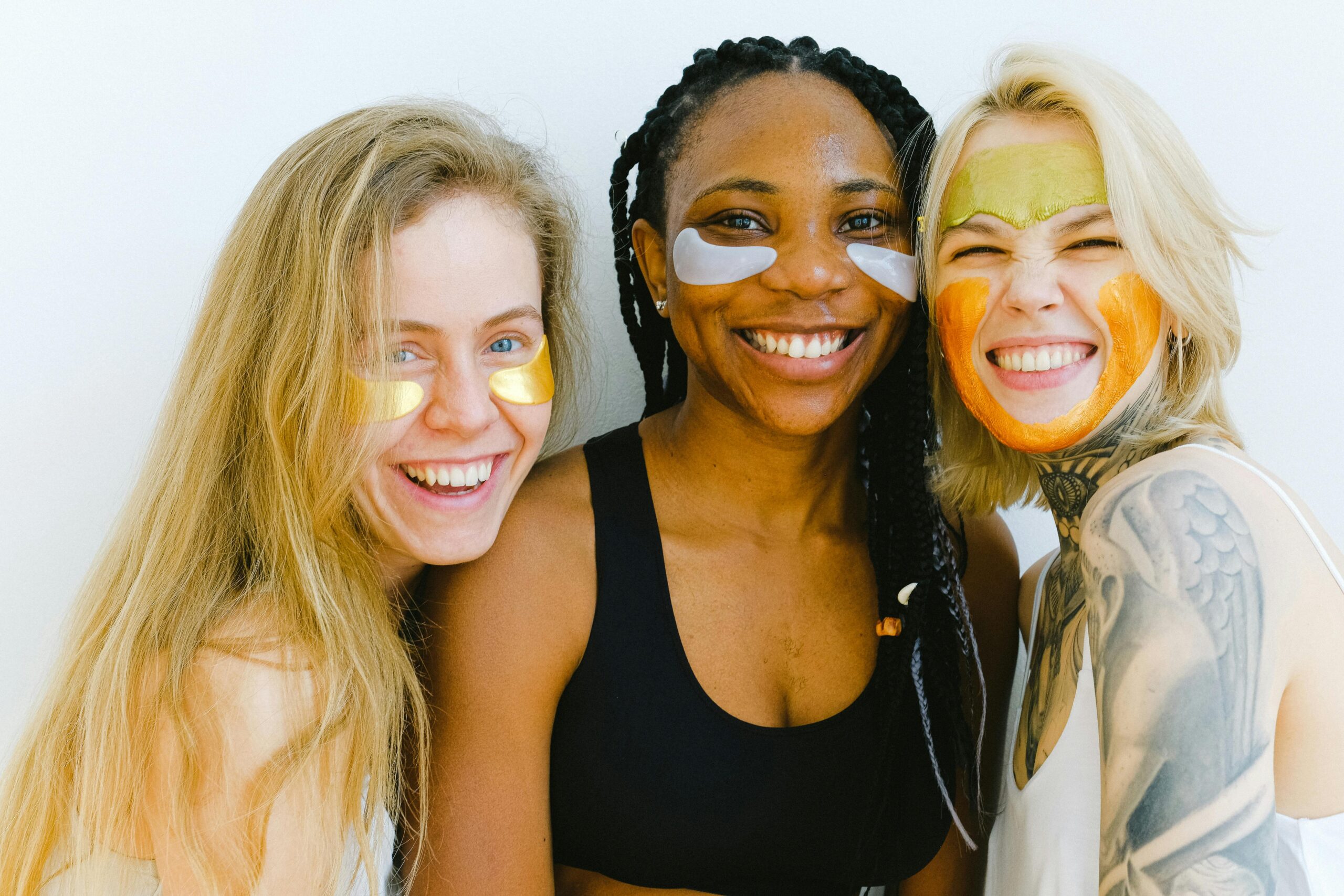 Three diverse women smiling with face masks.