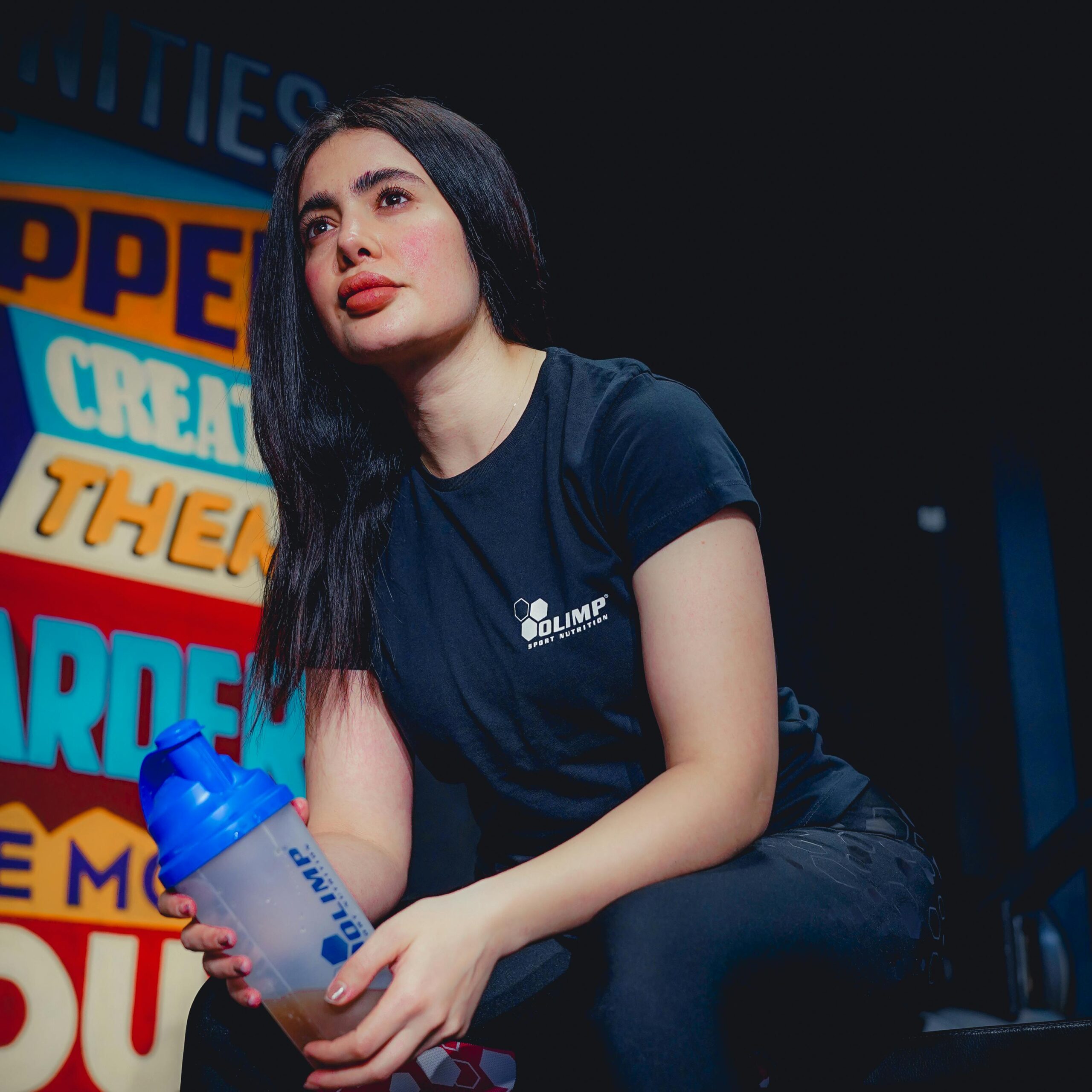 Woman in gym holding a protein shaker bottle.