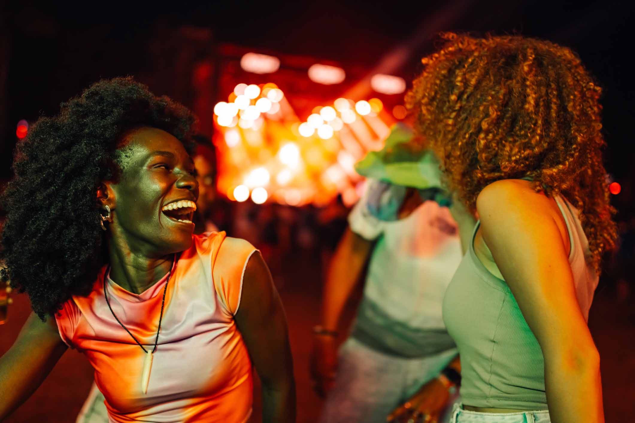Two women laughing and dancing at a concert.