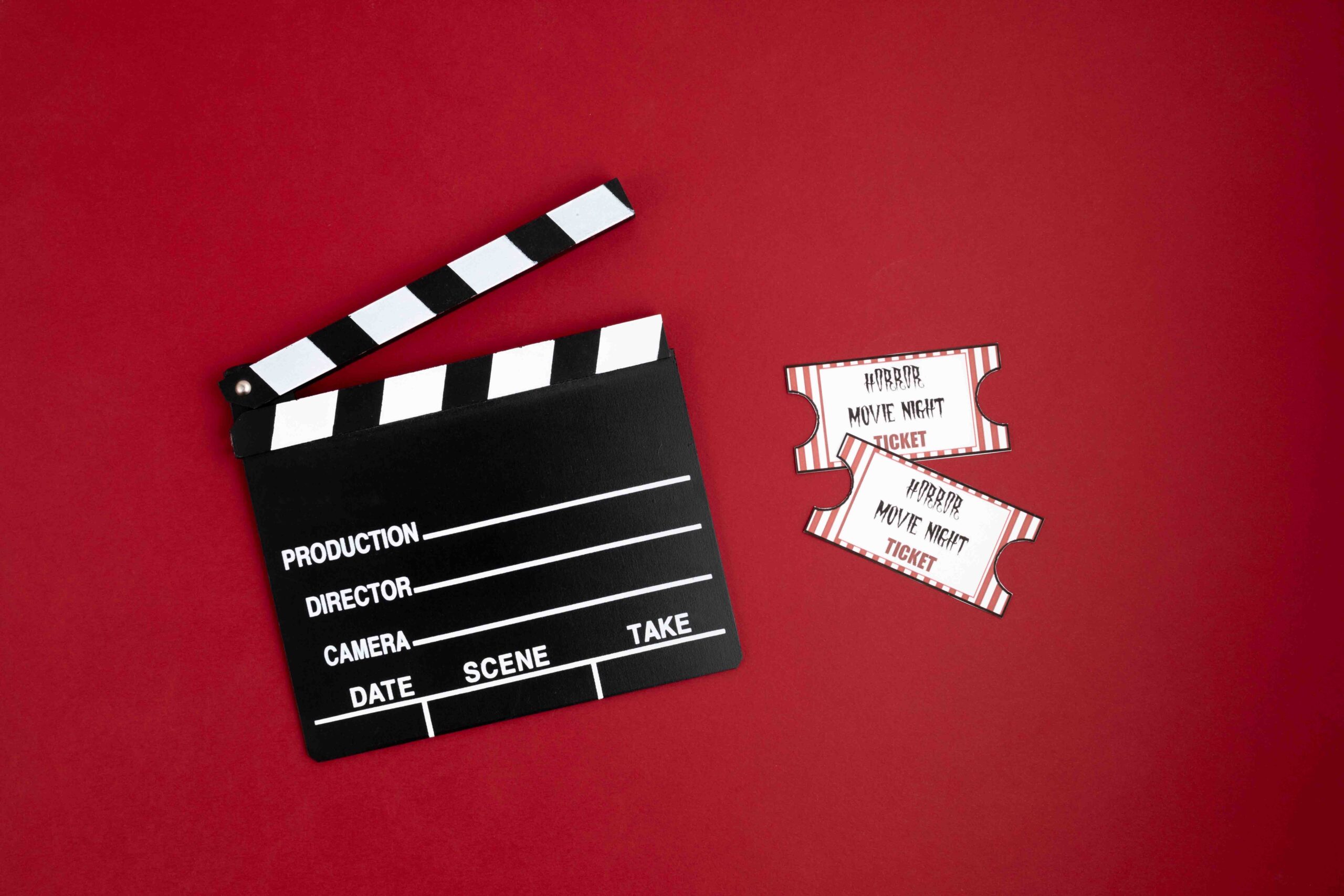 Clapperboard and movie tickets, red background.