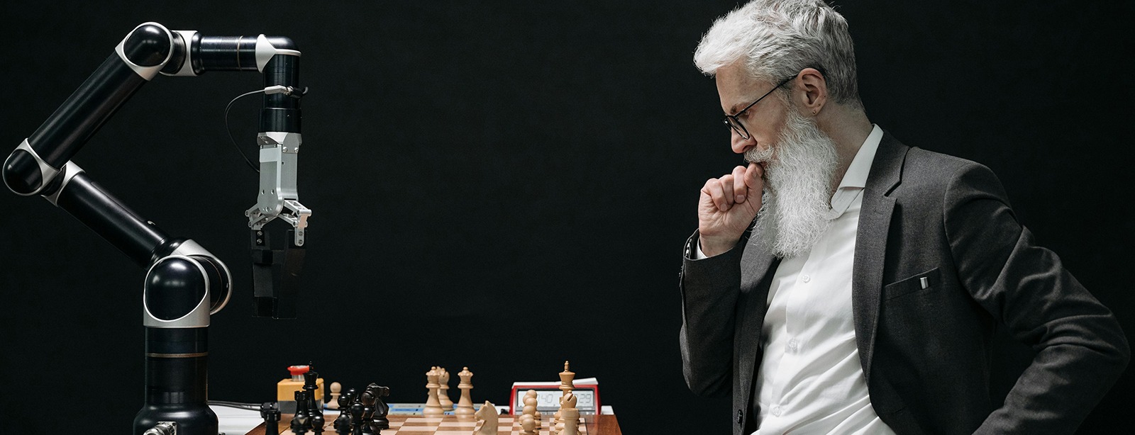An older man with a robotic arm playing chess