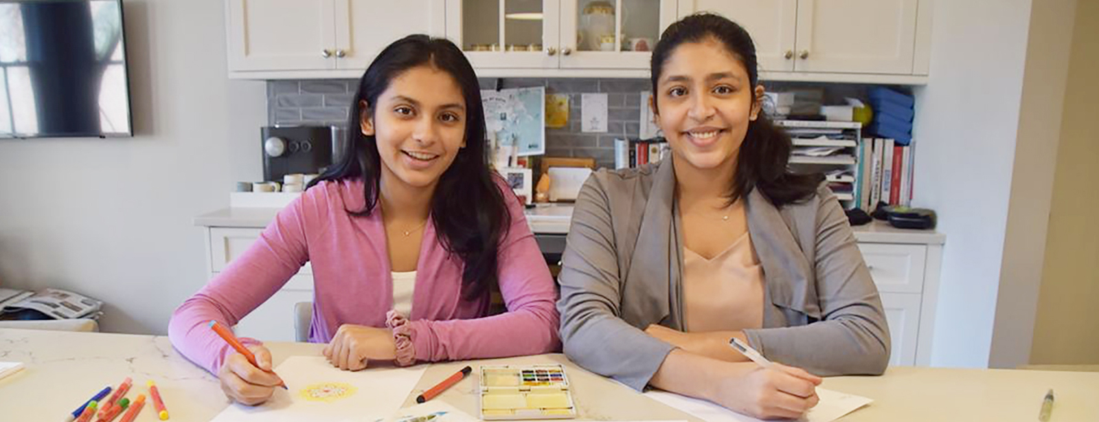 Two young women writing and drawing encouraging letters.
