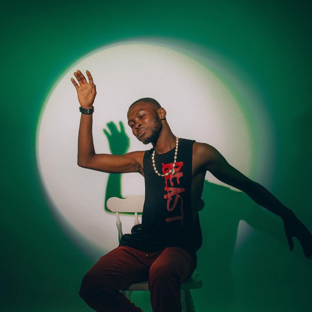 Man posing in spotlight on chair.