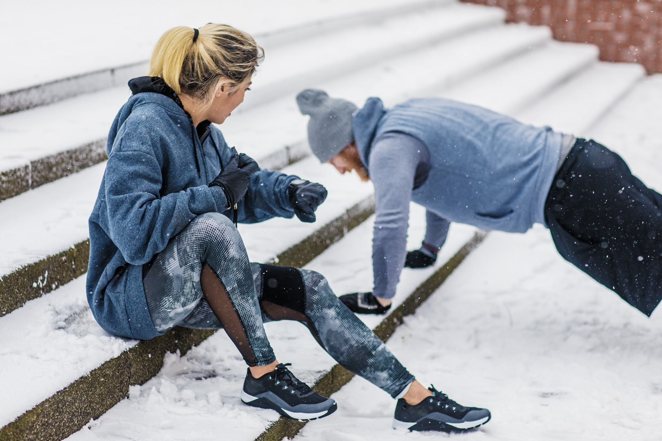 Two people exercising outdoors on snowy steps.