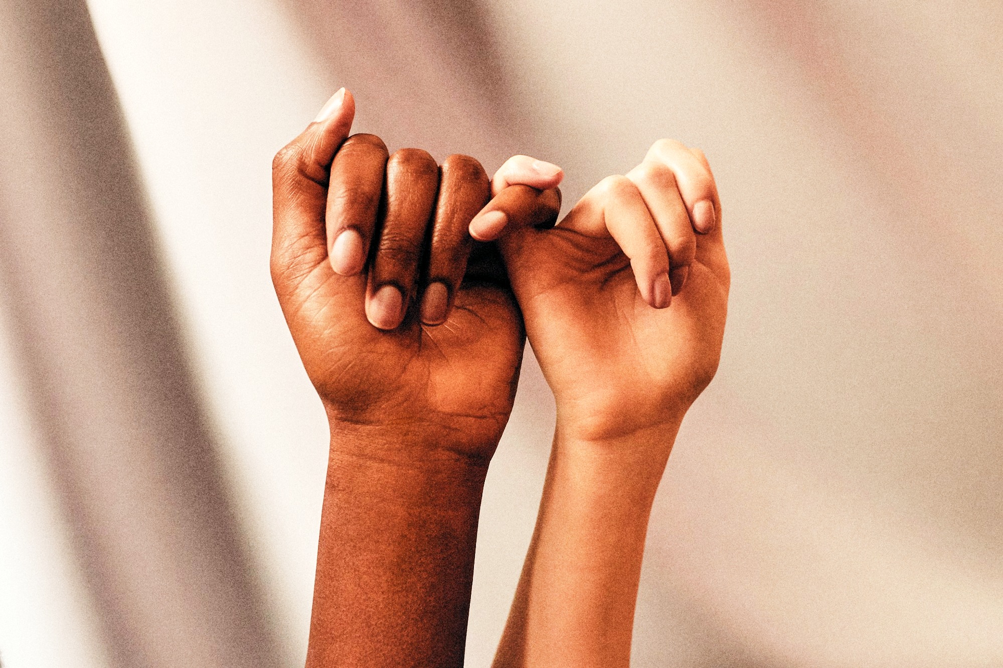 Two people making an interracial pinky promise