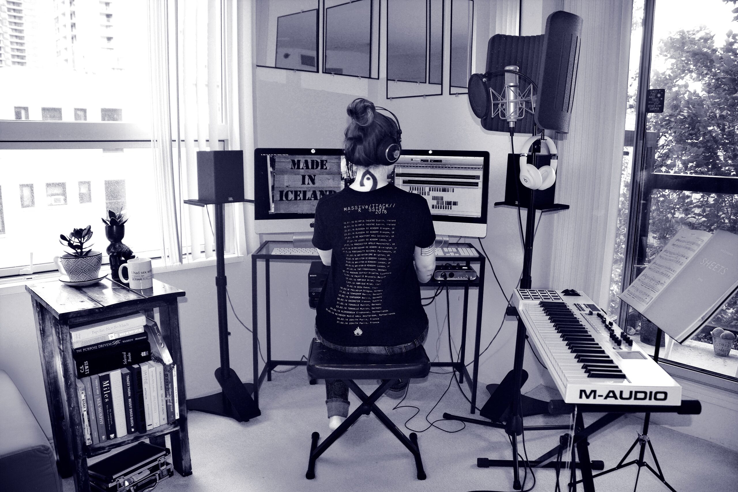 Woman sitting at a keyboard in a home studio.