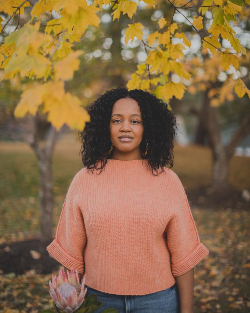 Yasmine Cheyenne standing outdoors under autumn leaves.
