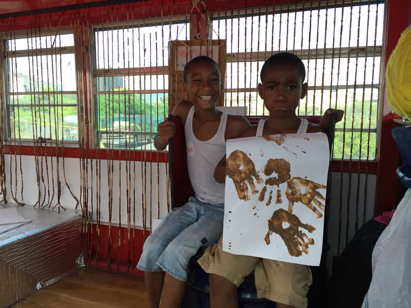 Two boys showing handprints art inside bus.