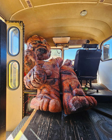 Large, rocky, orange carved figure inside a bus.