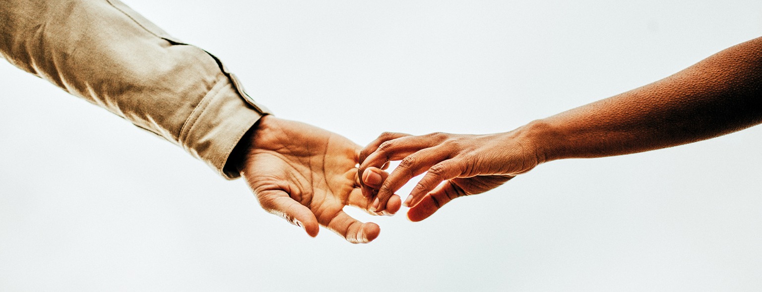 Romantic couple holding hands against a bright sky