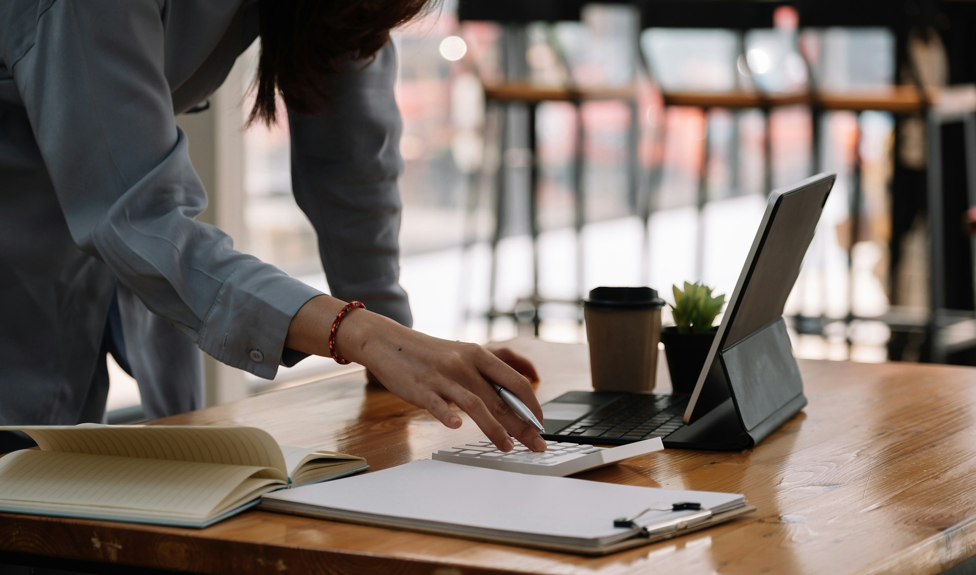 Woman using calculator and laptop for finances.