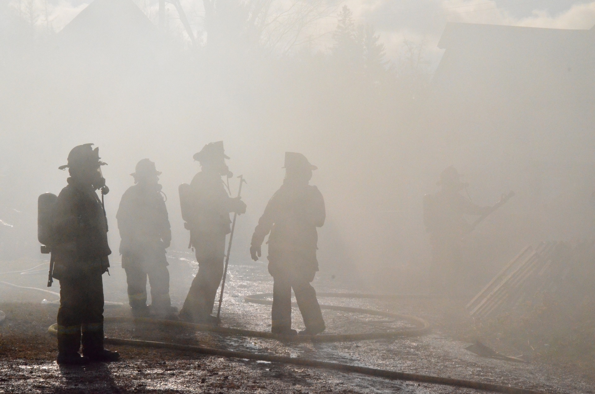 Firefighters standing in heavy smoke and haze.