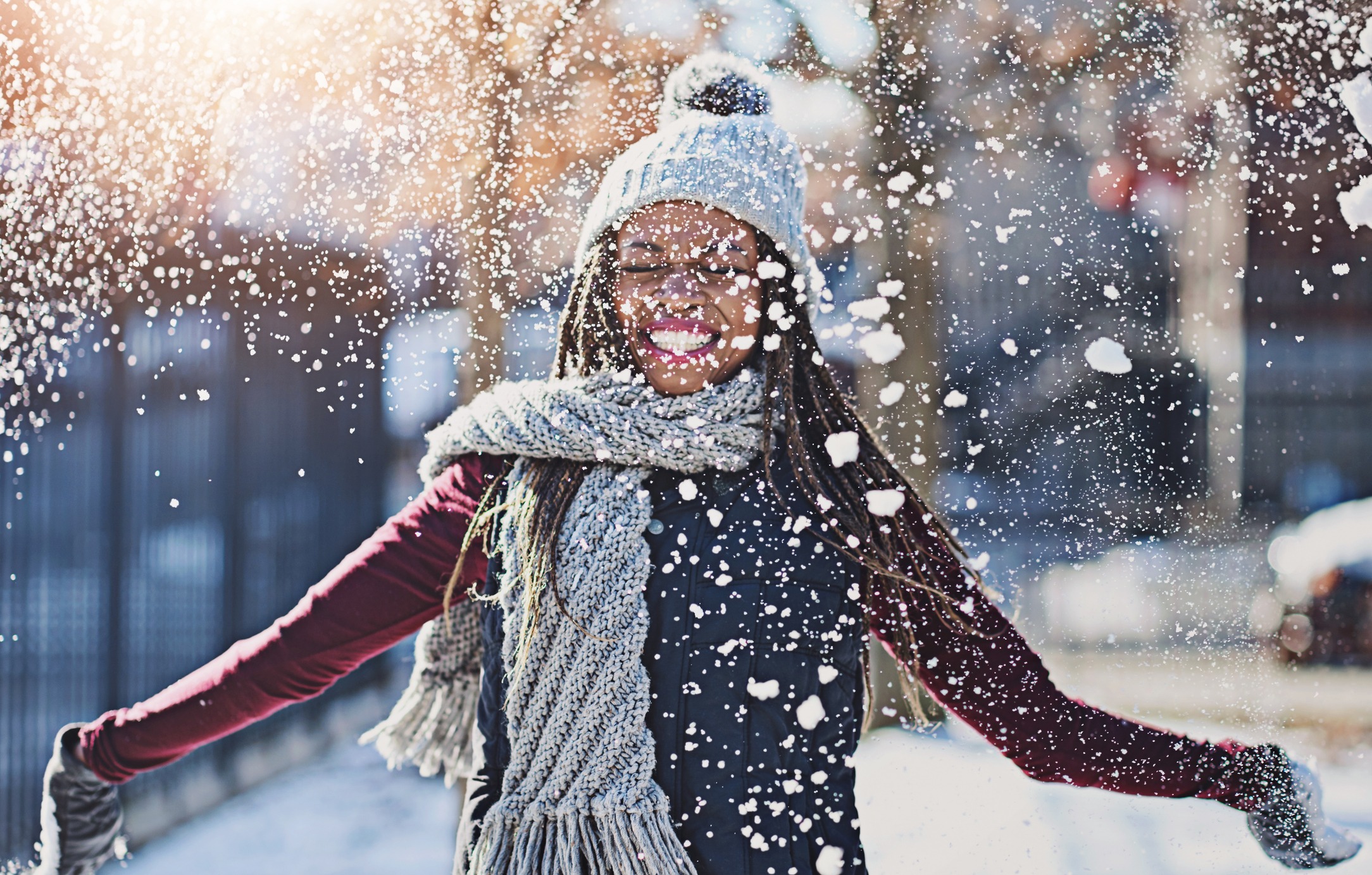 Happy woman enjoying snow fall outdoors in winter.