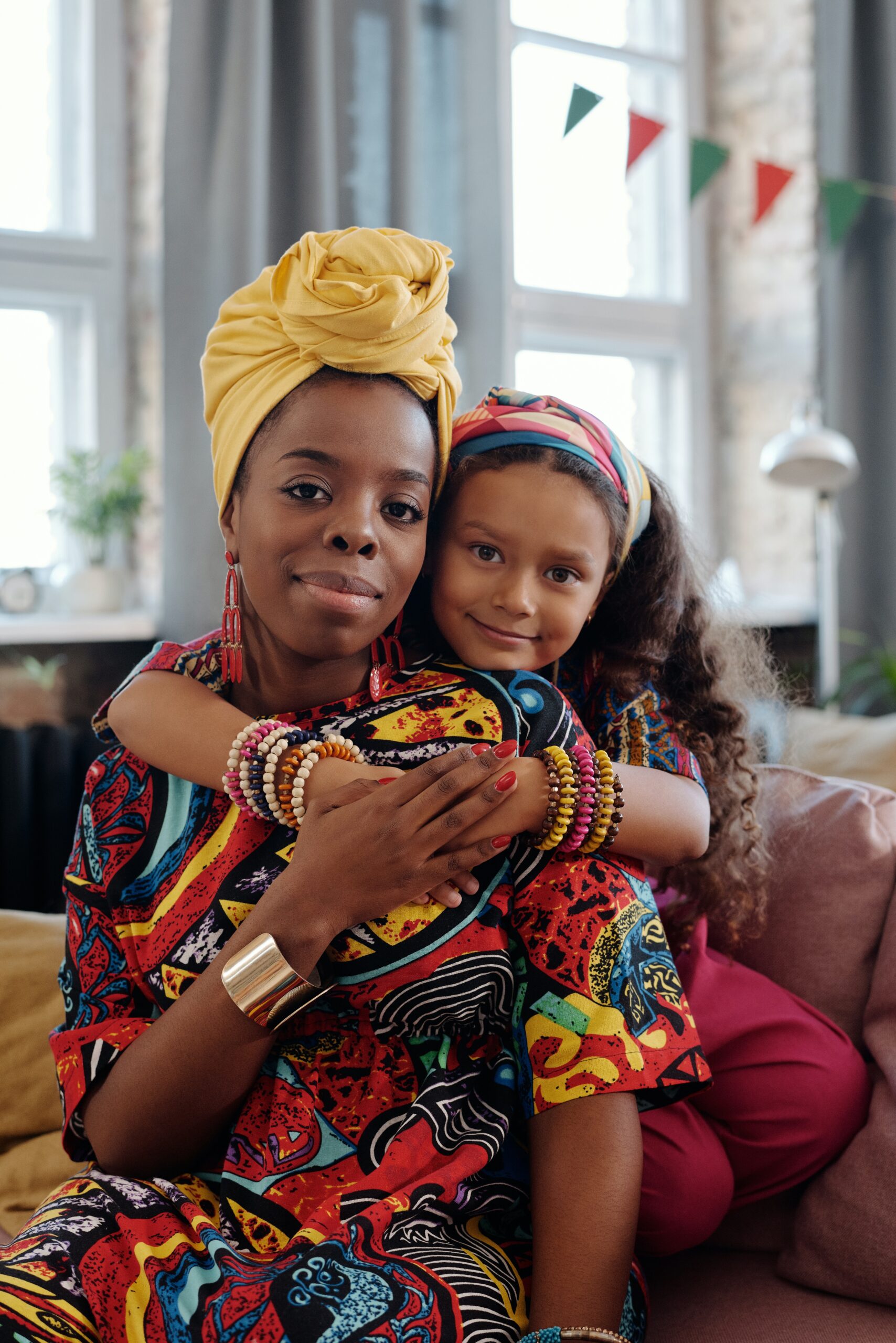Mother and daughter embracing in colorful Kwanzaa attire.