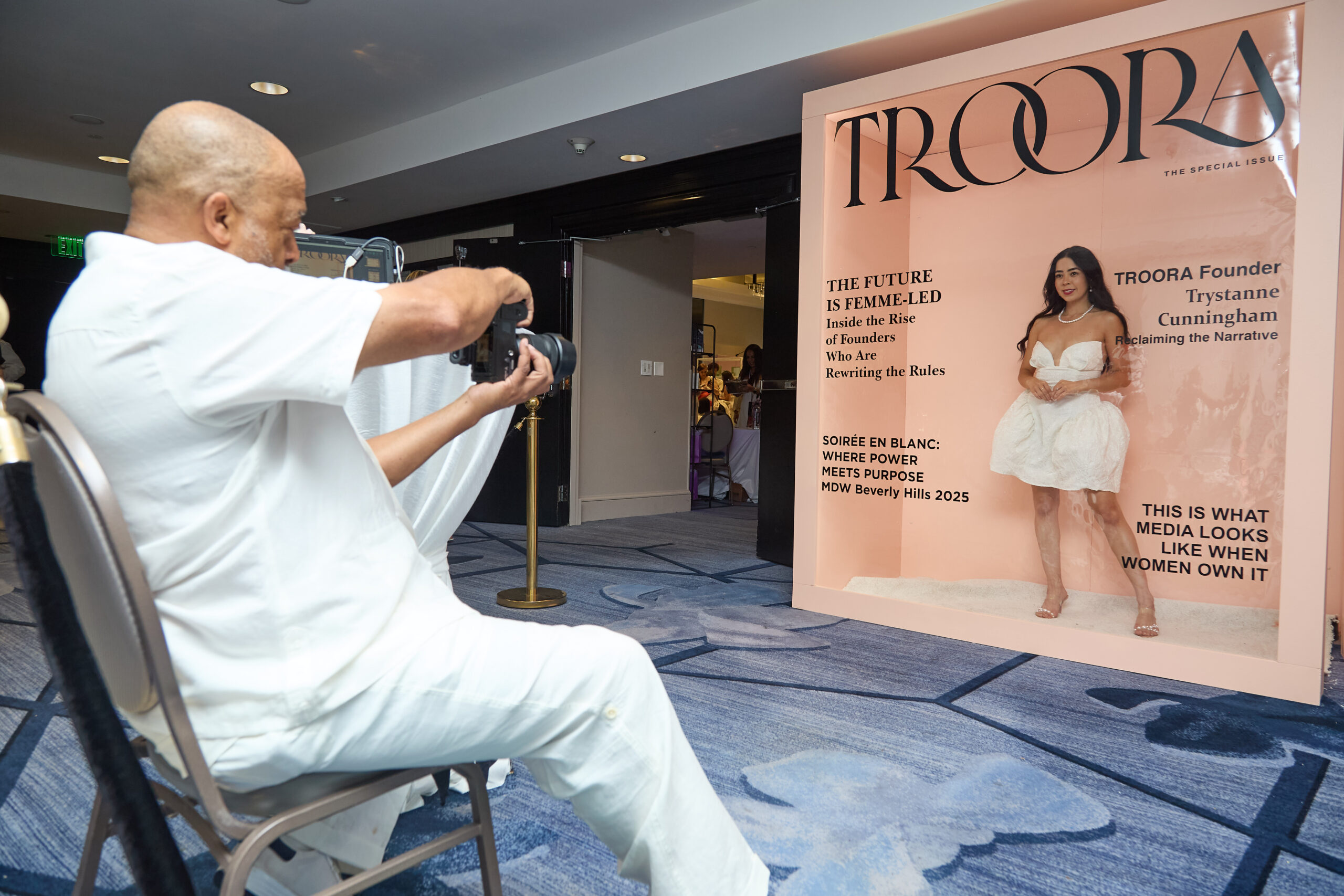 Photographer capturing woman posing against backdrop