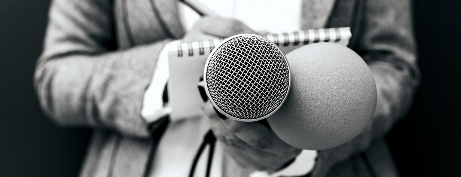 Woman holding microphone and taking notes