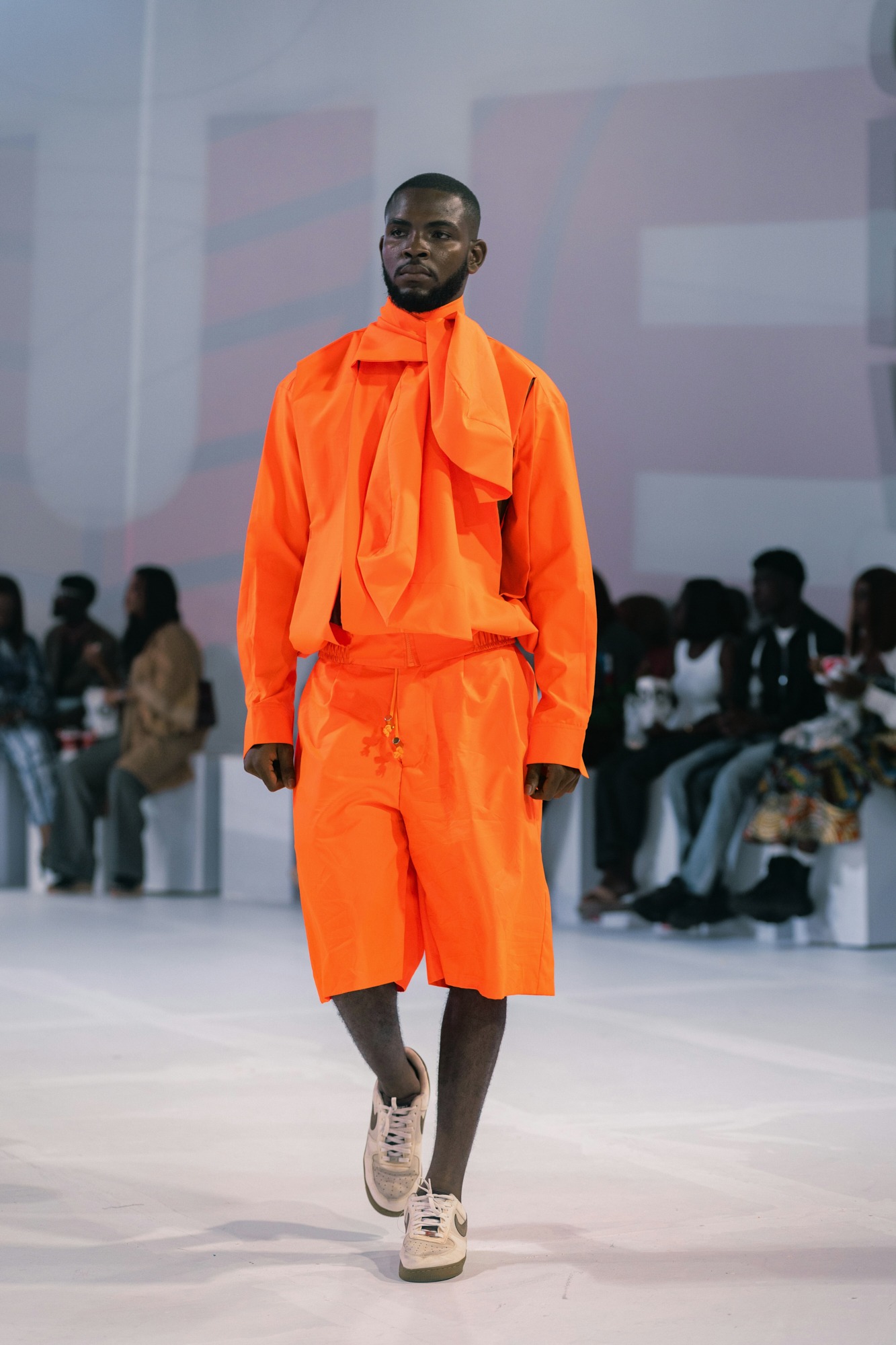Male model walking in bright orange outfit