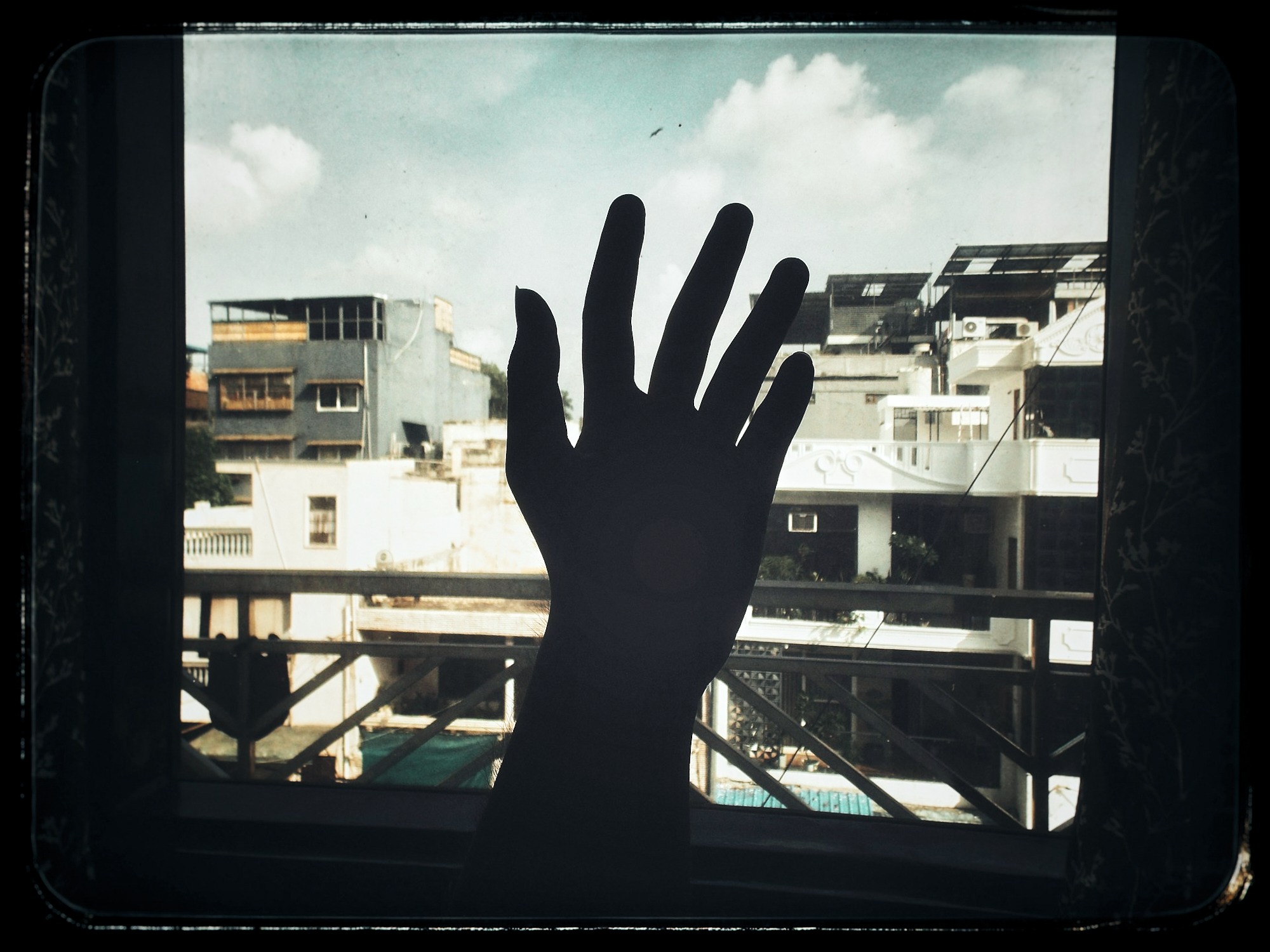 Silhouette of hand against cityscape by window