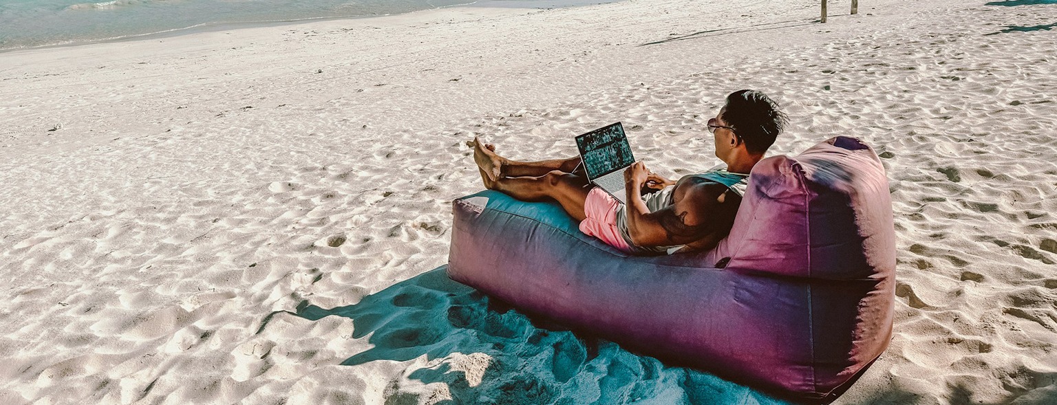 Person working on laptop on sunny beach