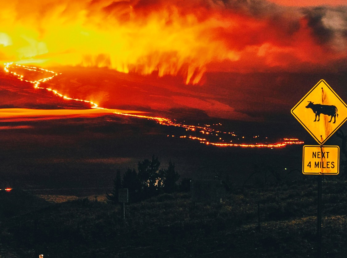 Road sign against dark sky and fireglow