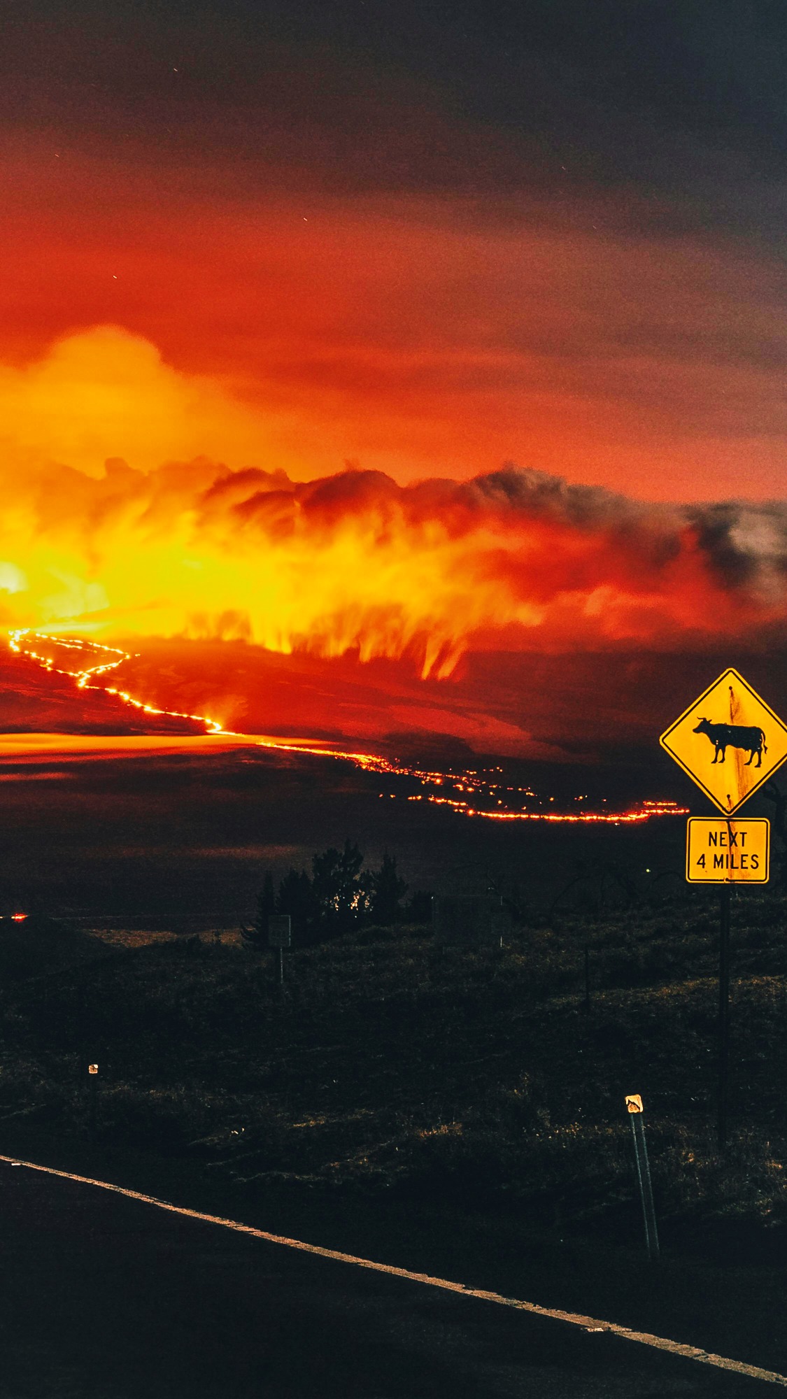 Road sign against dark sky and fireglow
