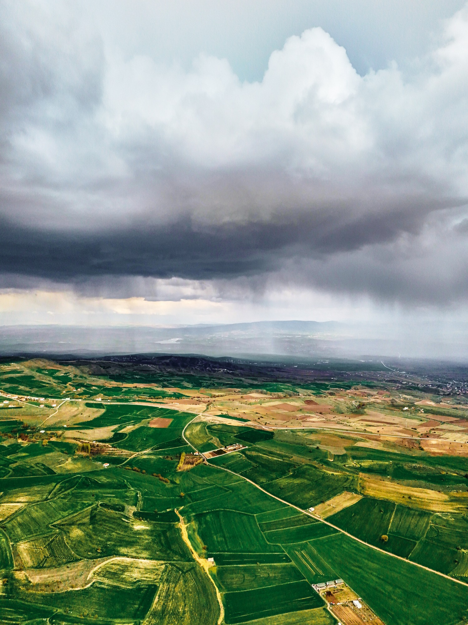 Aerial view of green fields under stormy clouds